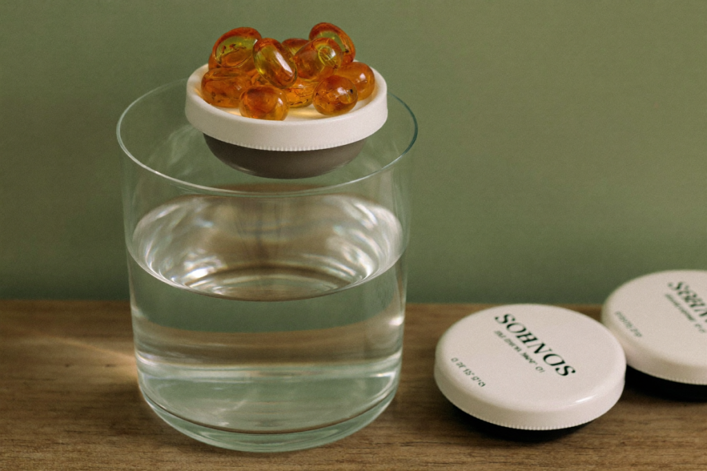 Unlabeled capsules beside a glass of water on a wooden surface