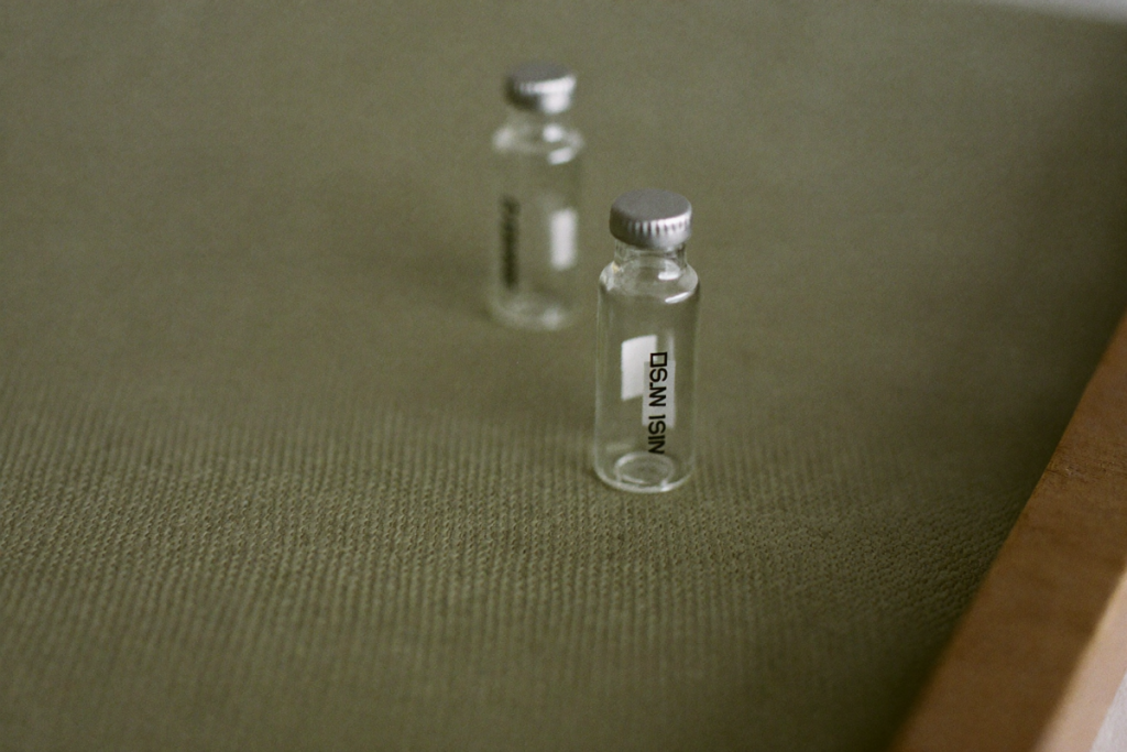 Two unlabeled vials side by side on sage linen suggesting a comparison