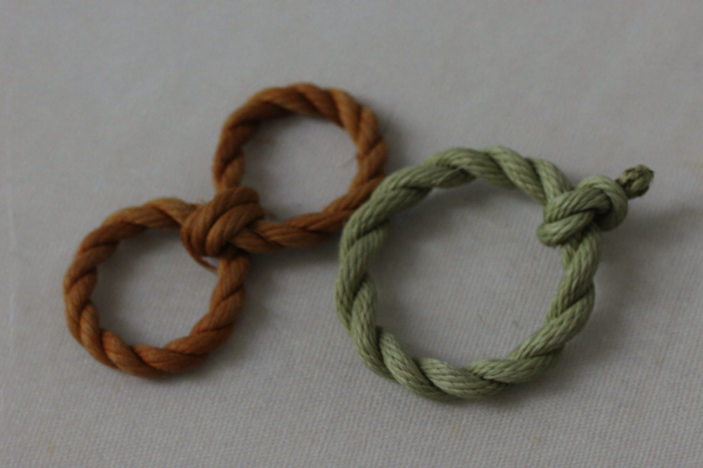 Two intertwined cords in earth-brown and sage-green representing the structural similarity between hCG and LH