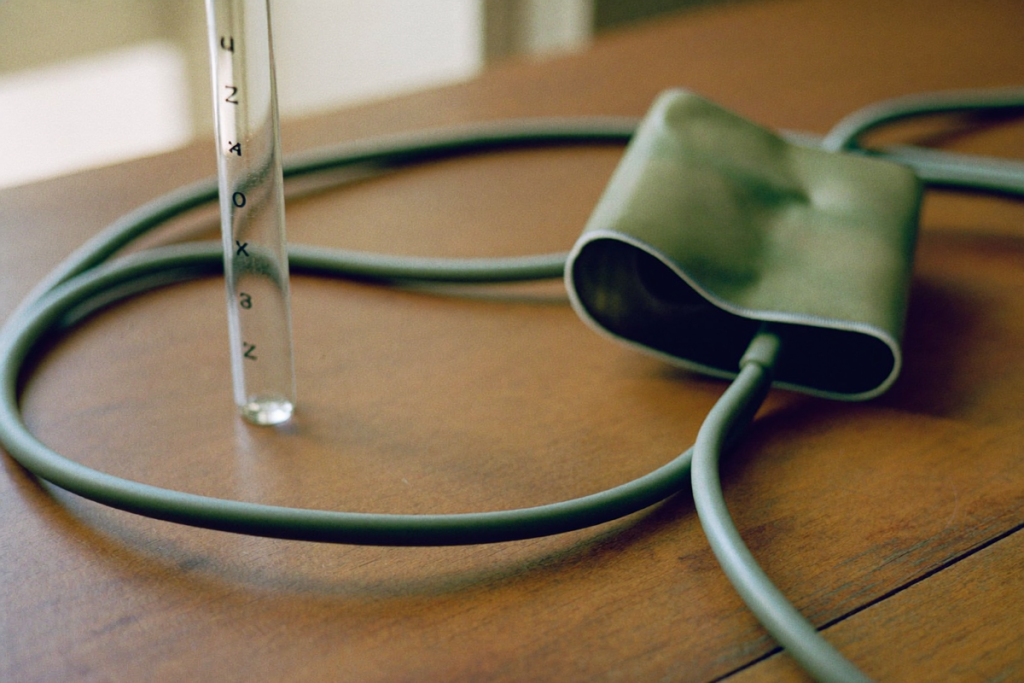 A blood-pressure cuff and an empty lab tube on a wooden table representing ongoing TRT safety monitoring
