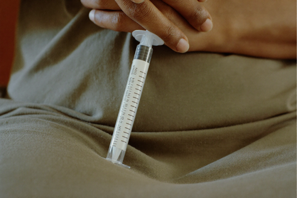 An unbranded injection pen resting near plain fabric suggesting abdomen, thigh, and upper arm sites