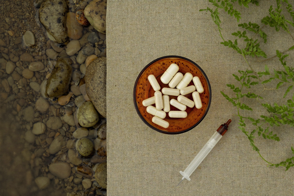 Overhead flat-lay of NAD+ precursor capsules with greenery and stones on linen