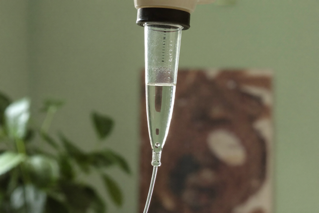 A slow IV drip chamber with a forming droplet, illustrating how infusion rate affects tolerability