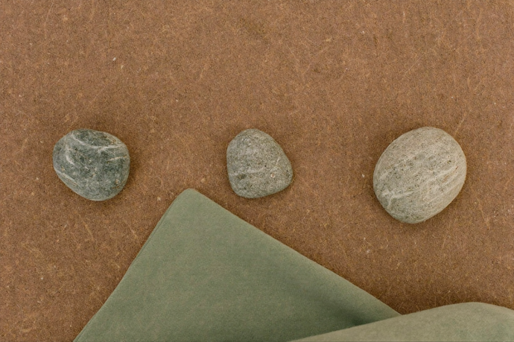 Three spaced stones arranged in an arc on linen, a visual metaphor for rotating injection sites