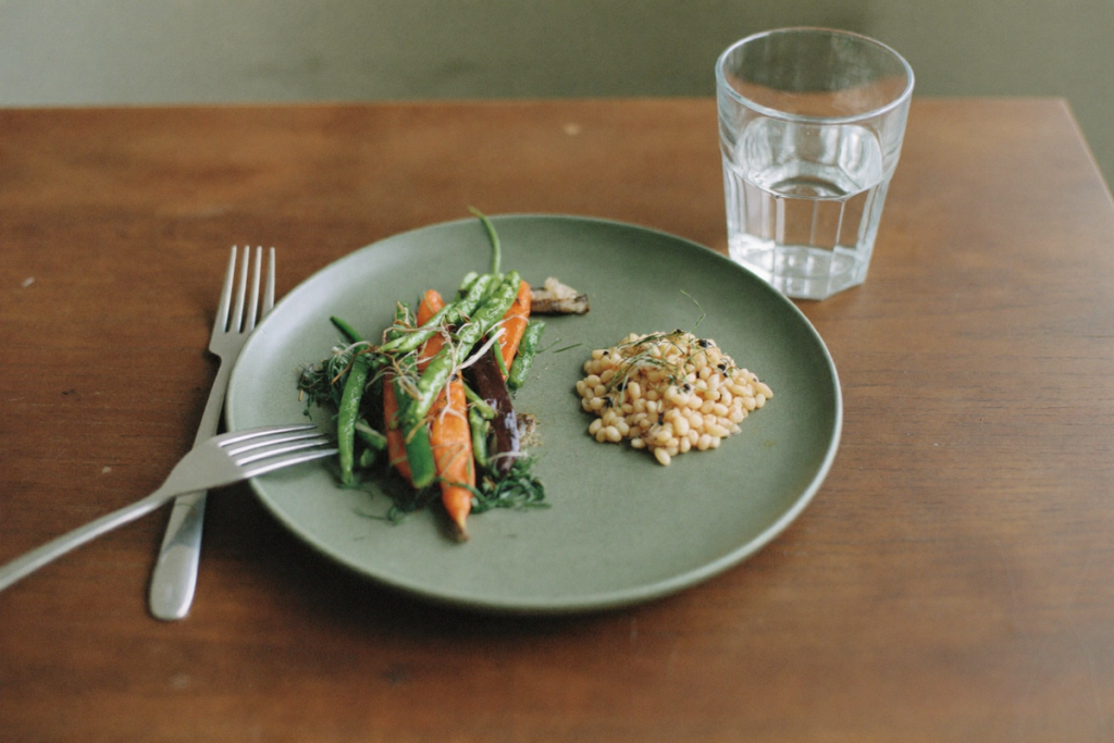 A small balanced plate of vegetables and grains with water, suggesting smaller portions and gentle eating