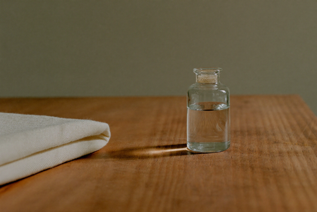 Single unlabeled clear vial on a wooden surface in warm earth tones