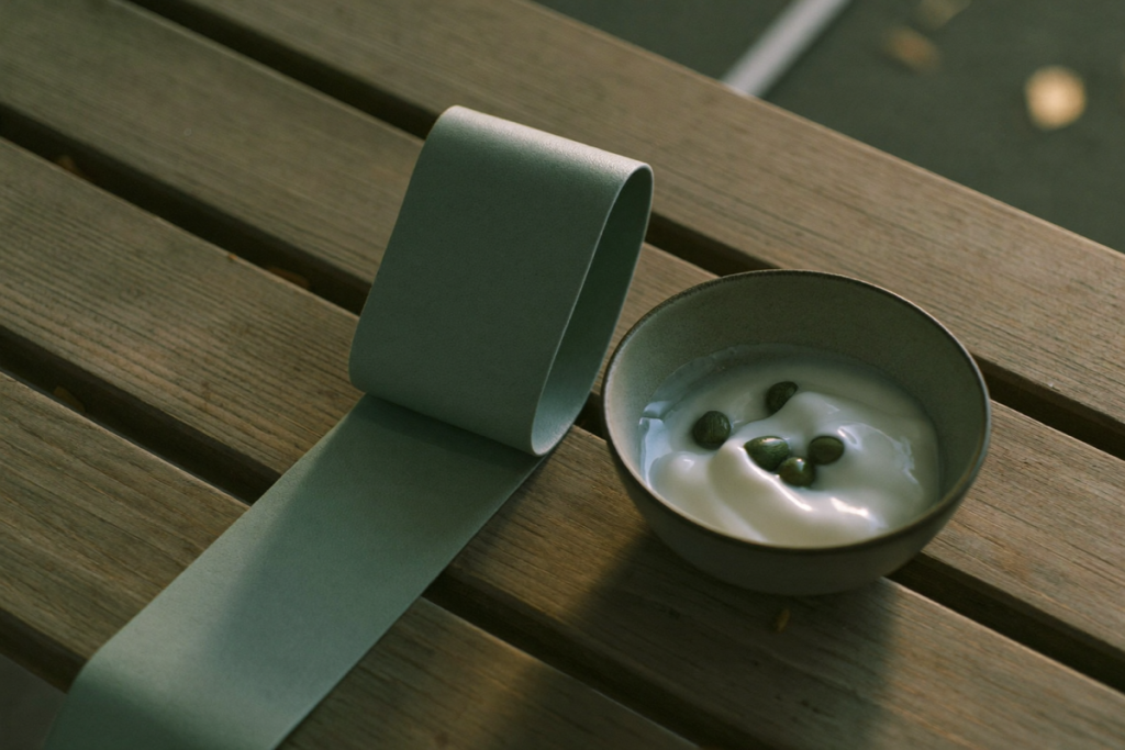 A resistance band and a bowl of plain protein-rich food on a bench in soft light, evoking muscle preservation