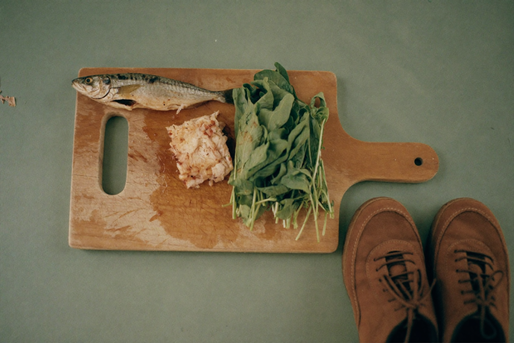 Leafy greens, a portion of fish, and walking shoes representing diet and physical activity alongside medication