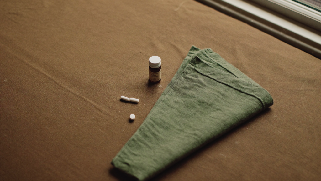 Amber prescription bottle and plain white oral tablets on a warm linen surface representing compounded enclomiphene