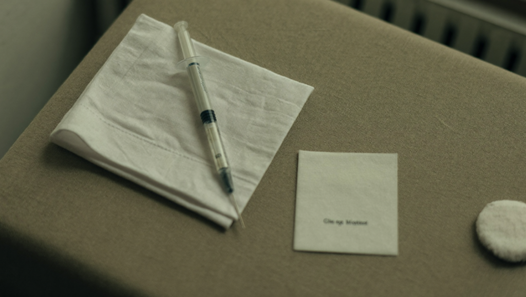 Unbranded weekly injection pen and an alcohol wipe arranged on plain linen, suggesting subcutaneous injection preparation