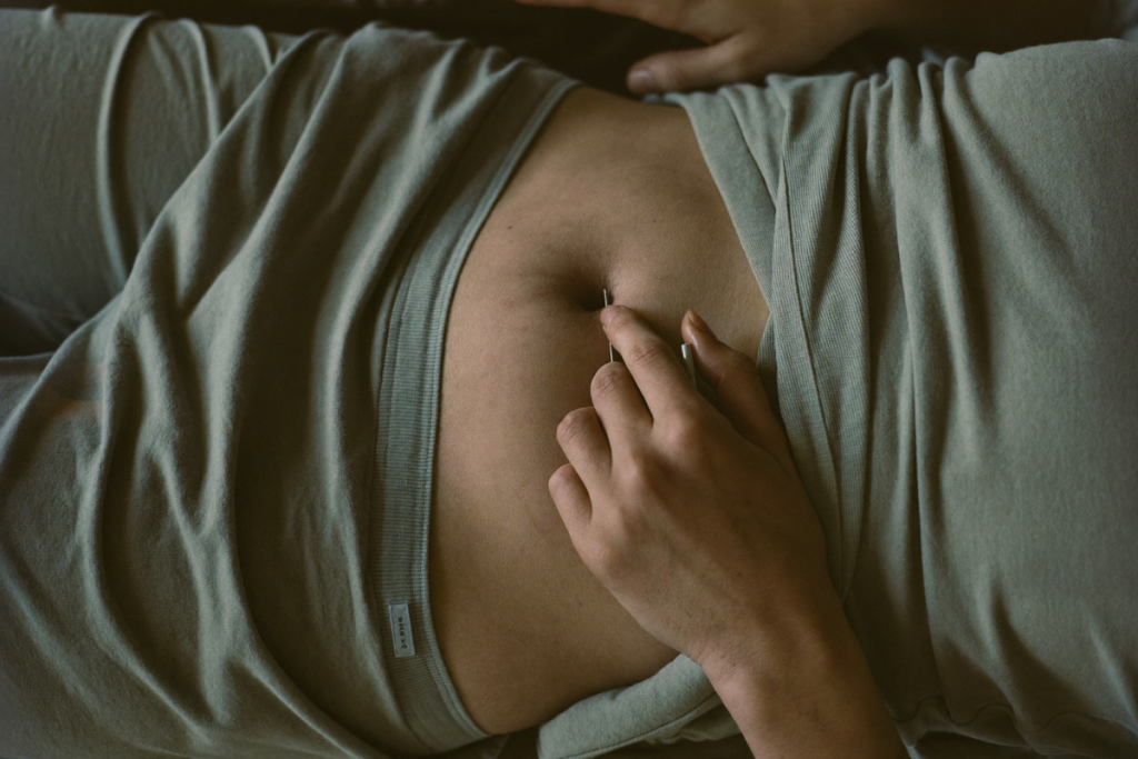A hand pinching a fold of abdominal skin to demonstrate a subcutaneous self-injection site