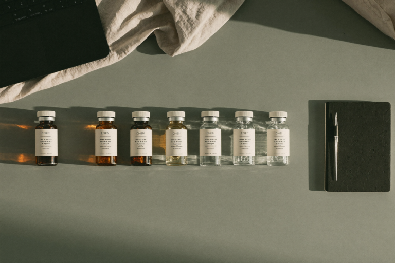 Unlabeled hormone-therapy vials, a laptop, and a notebook arranged on a sage-green desk, illustrating an online TRT clinic comparison