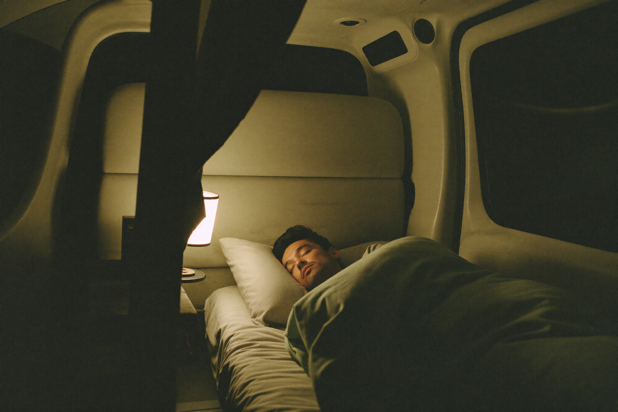 Truck driver resting in the sleeper berth of his cab at night